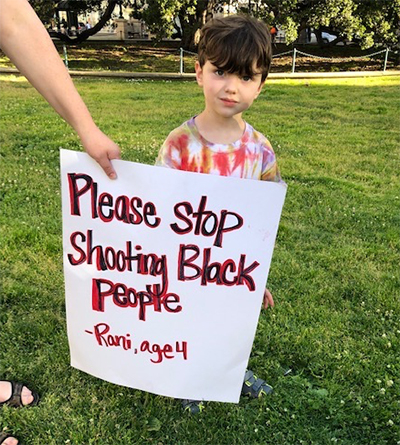 Child with sign that says Please stop shooting black people.